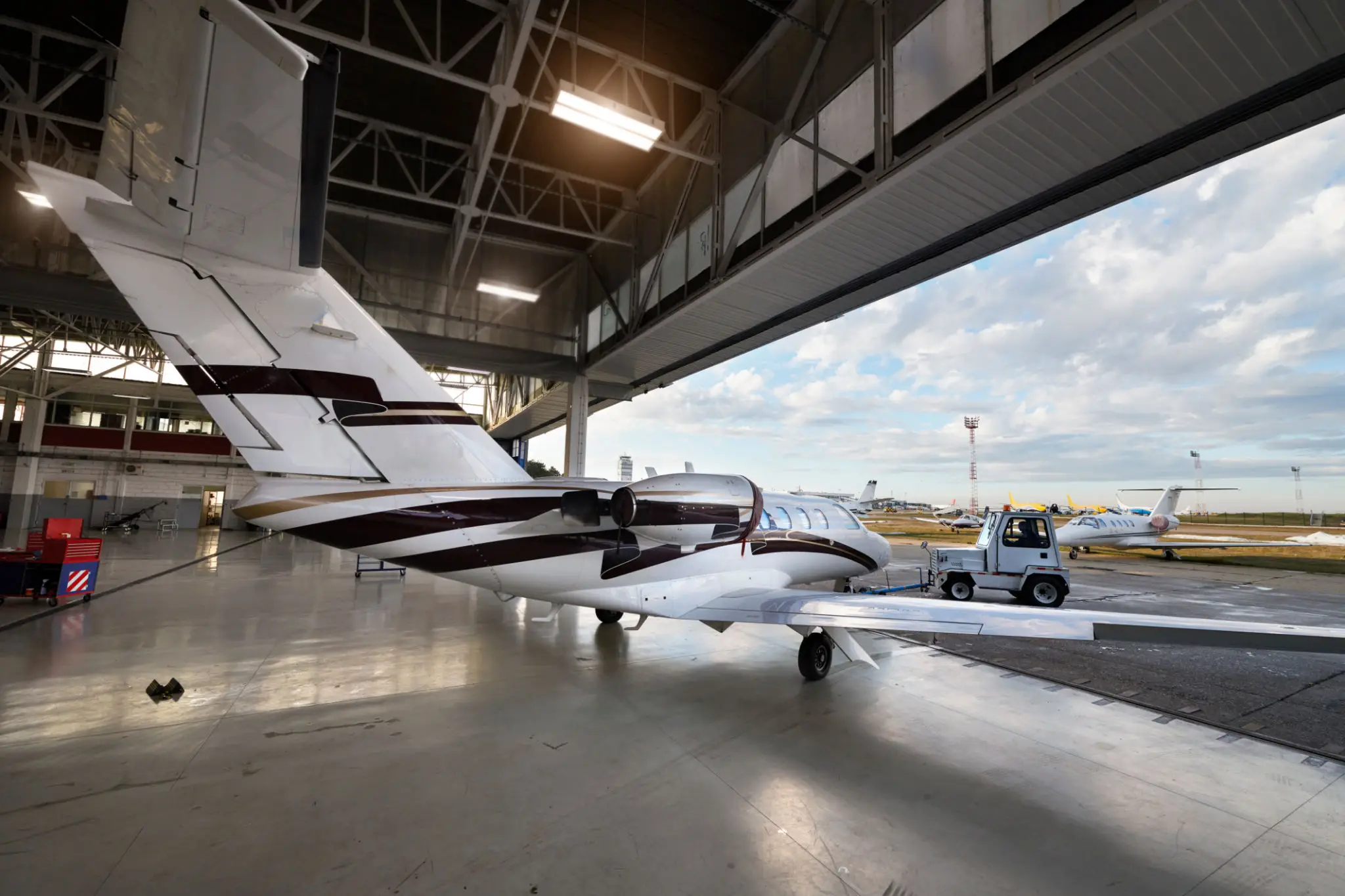 Private jet parked inside an aircraft hangar with open doors.