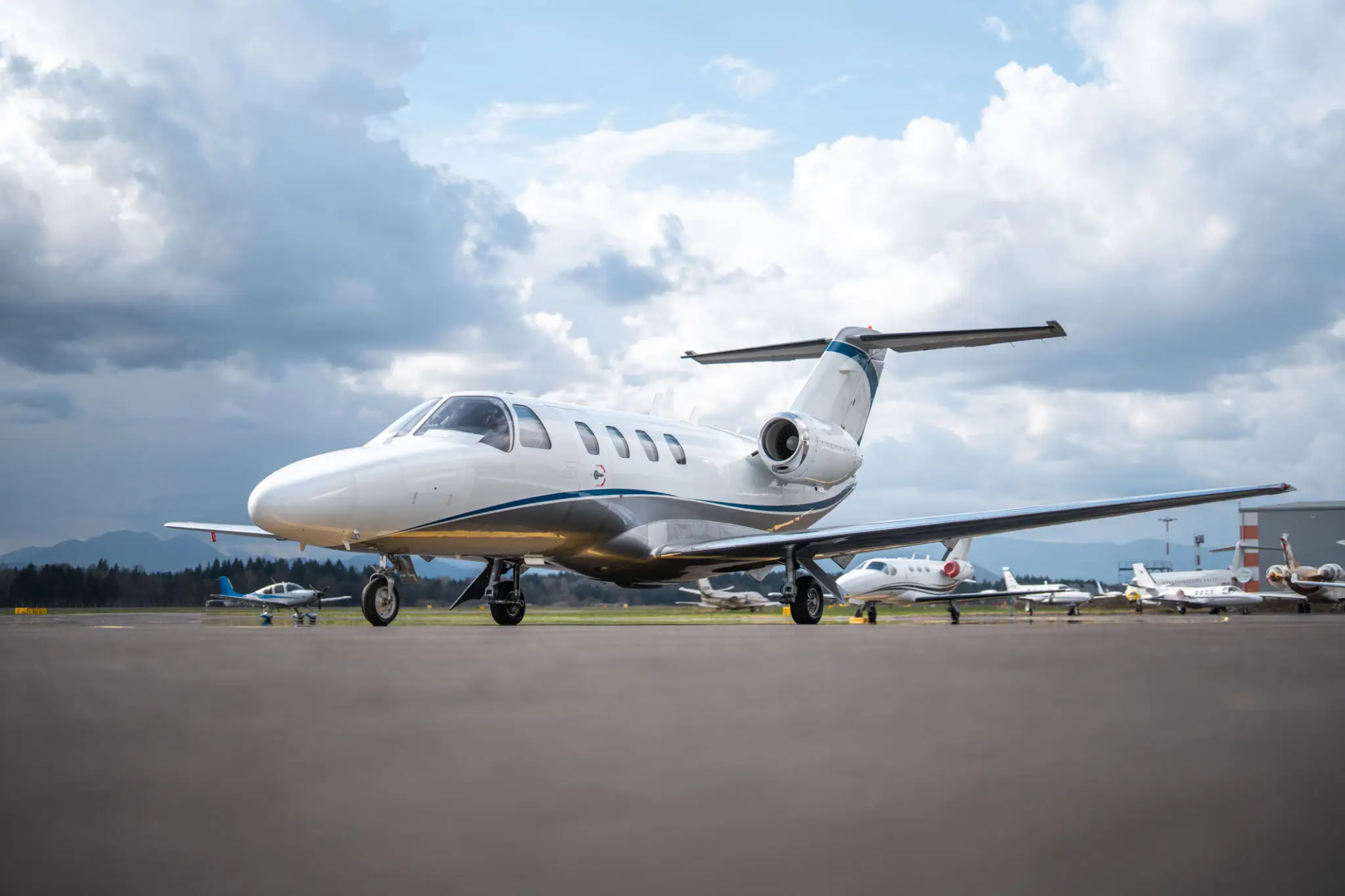 A sleek private jet parked on the runway under a cloudy sky.