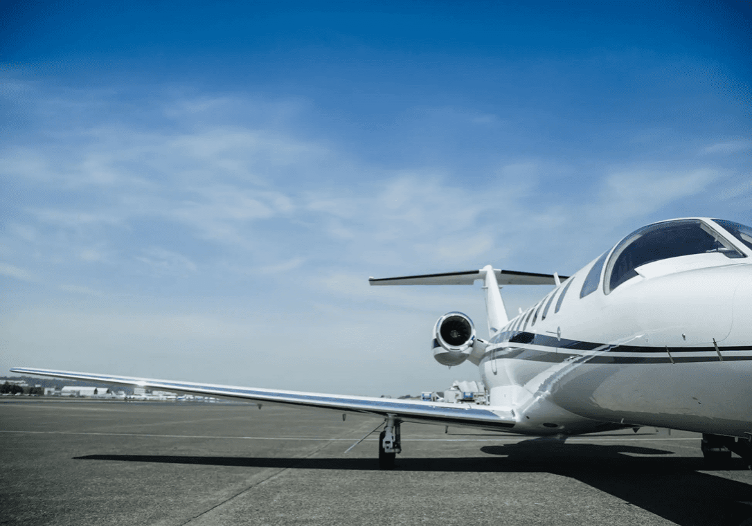 Private jet parked on an airport runway under a clear sky.